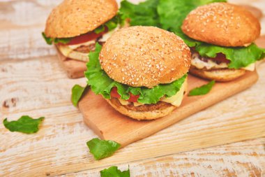 Işık arka planda ahşap masada zanaat sığır Burger. Sokak Yemeği, Fast Food. Peynir ve ahşap masada ev yapımı sulu hamburgerler. Boşluk Kopyala.