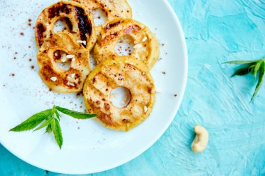 Mavi arka planda beyaz plaka üzerinde cinamon ile ızgara elma. Izgara tatlı. Barbekü meyvesi. Kopya alanı. Sağlıklı yiyecekler. Vegan gıda.