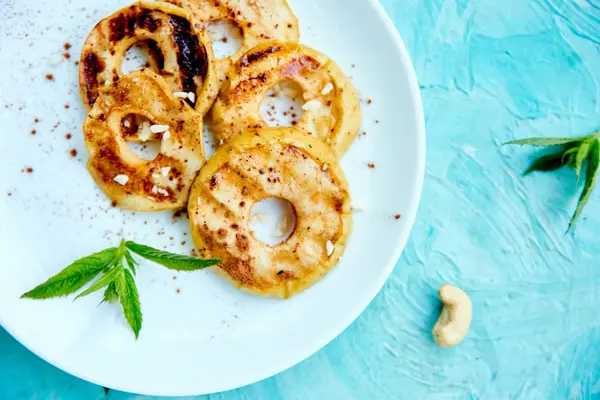 Mavi arka planda beyaz plaka üzerinde cinamon ile ızgara elma. Izgara tatlı. Barbekü meyvesi. Kopya alanı. Sağlıklı yiyecekler. Vegan gıda.