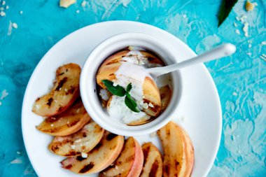 Mavi arka planda beyaz tabakta dondurma lı ızgara şeftali. Izgara tatlı. Barbekü meyvesi. Kopya alanı. Sağlıklı yiyecekler. Vegan gıda.