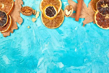 Sonbahar kompozisyonu arka planında mavi bir zemin üzerinde kurumuş portakal, yaprak ve tarçın dilimleri, sonbahar konsepti, düzlük, üst görünüm