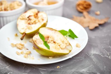 Ballı armut rostosu ve gri arka plan masasında beyaz tabakta ceviz..