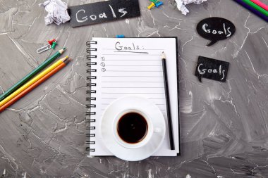 Fikir ile not defteri, buruşturulmuş kağıt, gri arka plan üzerinde kahve fincan gibi hedefler. Üstte görüntü.