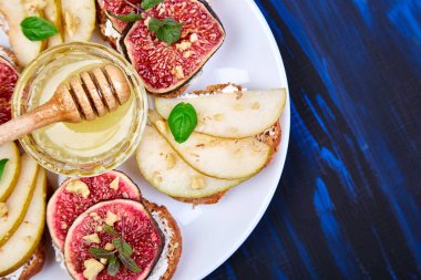 Armut, ricotta peyniri, bal, incir, fındık ve şifalı otla Kahvaltı tostları ya da atıştırmalık sandviçler. Antipasto. İtalyan yemeği. Üst Manzara. Boşluğu kopyala.