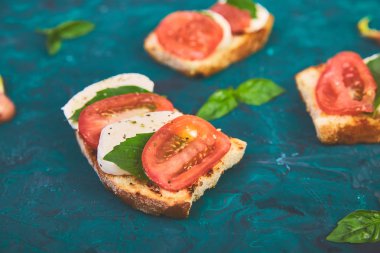 Caprese Bruschetta tost. Domates ile Bruschetta, mozzarella peynir ve yeşil bir arka planda fesleğen. Geleneksel İtalyan meze veya snack, meze