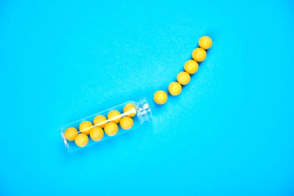 医療ブログのためのミニマリズムスタイルのテンプレート 小さなガラス瓶は 小さな黄色の錠剤が青い背景をこぼしました 医薬品の概念 薬の薬フラットラ — ストック写真