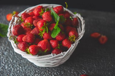 Siyah arka planda olgun kırmızı çilekler, beyaz sepette çilekler. Taze çilek. Güzel çilekler. Diyet yemek. Sağlıklı, vejetaryen. Boşluğu kopyala. 