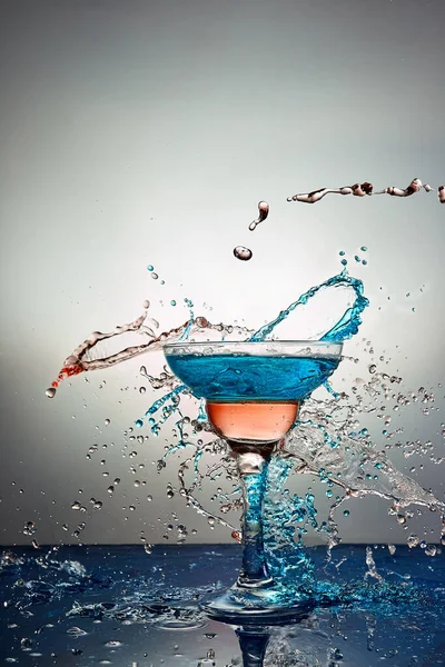 Glass with blue and yellow champagne or cocktail. Levitation — Stock Photo, Image