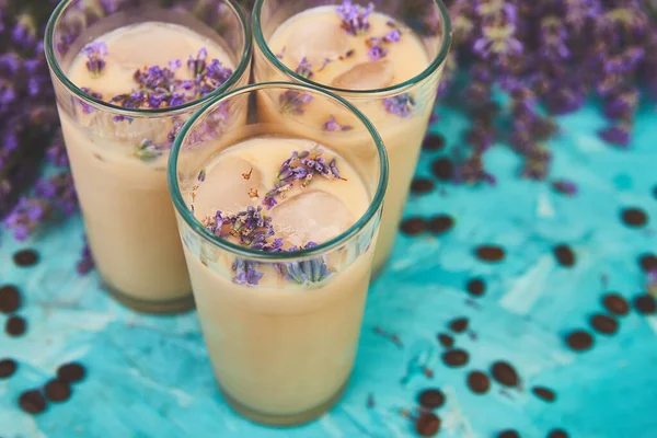 Yaz içeceği buzlu kahve bardakta lavanta ve mavi arka planda kahve çekirdekleri. Günaydın konsepti. Baharatlı buzlu kahve.