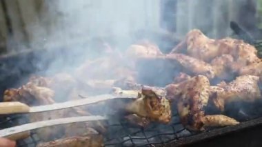 Mangal ve açık havada ızgara yapılan tavuk kanatları için metal maşa kullanan adam, mangal ızgarasında kızartılan et, arka bahçede pişirilen aşçı..