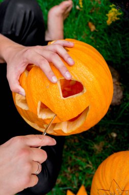 Balkabağını bıçakla kesen ve balkabağı feneri hazırlayan bir adamın eli. Cadılar Bayramı. Parti için dekorasyon.