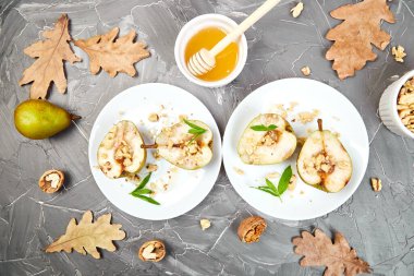 Ballı armut rostosu ve gri arka plan masasında beyaz tabakta ceviz..