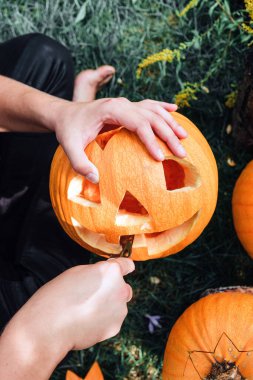 Balkabağını bıçakla kesen ve balkabağı feneri hazırlayan bir adamın eli. Cadılar Bayramı. Parti için dekorasyon. Renkli fotoğraf.