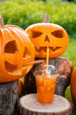 Arka planda balkabağı desenli Cadılar Bayramı kokteyli. Parti için yumruk. Jack-o-Lantern kokteyl içiyor..