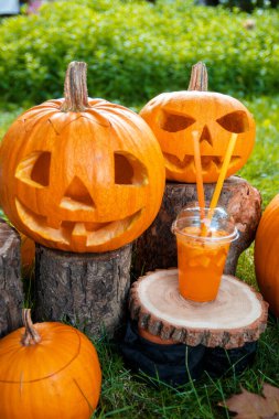 Arka planda balkabağı desenli Cadılar Bayramı kokteyli. Parti için yumruk. İki Jack-o-Lantern kokteyl içiyor..