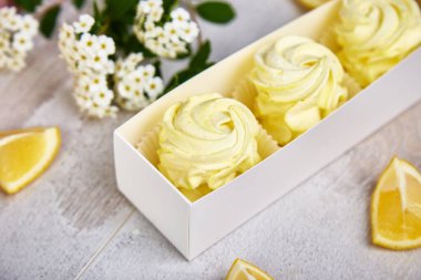 Ev yapımı limon sarısı marşmelovlu hediye kutusu. Çiçek şeklinde elma zephyr. Gül şeklinde. Beyaz ahşap masada lezzetli meyveli tatlı..