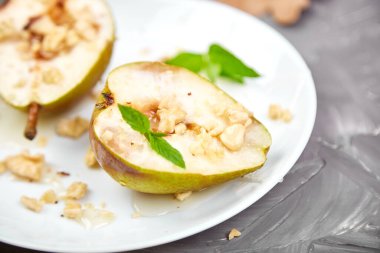 Ballı armut rostosu ve gri arka plan masasında beyaz tabakta ceviz..