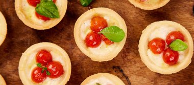 Tahta üzerinde mozzarella peyniri olan vişneli domatesli Mini turtalar. Üst Manzara. Boşluğu kopyala.