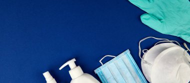 Düz Coronavirus koruması, tıbbi koruyucu maskeler, eldivenler, el dezenfekte şişeleri, antiseptik, dezenfeksiyon, mavi arka planda sprey, kopyalama alanı.