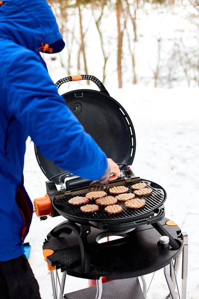 Man grilling steaks on a portable BBQ, Snowy winter barbecue — Stock Photo, Image