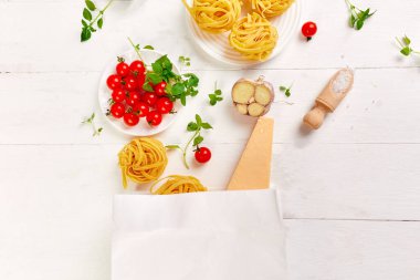 Bakkal poşetindeki sağlıklı yiyecekler, beyaz arka planda İtalyan makarnası pişirmek için gerekli malzemeler, market alışverişi, sağlıklı beslenme, akşam yemeği konsepti. Boşluğu kopyala