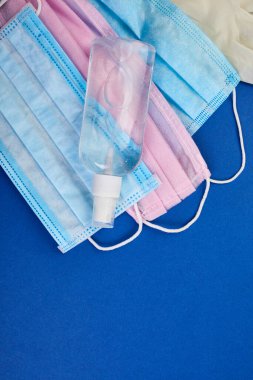 Düz Coronavirus koruması, tıbbi koruyucu maskeler, eldivenler, el dezenfekte şişeleri, antiseptik, dezenfeksiyon, mavi arka planda sprey, kopyalama alanı.