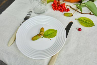 Şükran Günü ya da Cadılar Bayramı yemek masası. Kabak, meşe palamudu, armut yaprakları beyaz masa örtüsü armut, yukarıdan manzara, düz yatış.