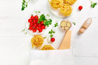 Bakkal poşetindeki sağlıklı yiyecekler, beyaz arka planda İtalyan makarnası pişirmek için gerekli malzemeler, market alışverişi, sağlıklı beslenme, akşam yemeği konsepti. Boşluğu kopyala