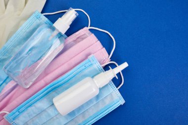 Düz Coronavirus koruması, tıbbi koruyucu maskeler, eldivenler, el dezenfekte şişeleri, antiseptik, dezenfeksiyon, mavi arka planda sprey, kopyalama alanı.