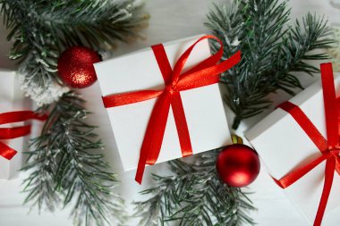 Noel hediyesi kutusu, köknar ağacı dalları, beyaz ahşap arka planda kırmızı süslemeler, Noel, kış, yeni yıl konsepti, düz döşeme, üst manzara, kopyalama alanı