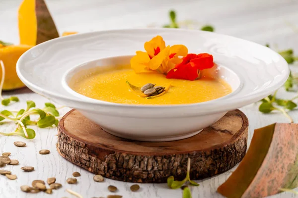 Ukraynalı mutfağı. Kabak püresi çorba, krem, kabak çekirdeği ve çiçeklerle beyaz tabakta. Kopya alanı, seçici odak