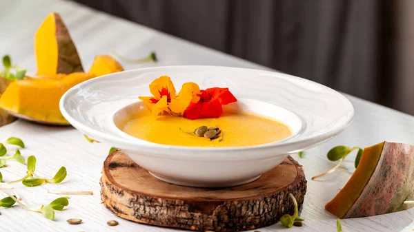 Ukraynalı mutfağı. Kabak püresi çorba, krem, kabak çekirdeği ve çiçeklerle beyaz tabakta. Kopya alanı, seçici odak