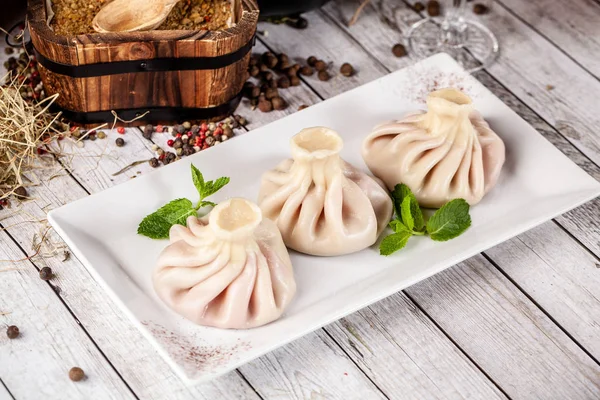 Geleneksel Gürcü ve Ermeni mutfağı. Gürcü Hıngel bir restoranda ahşap bir masa üzerinde beyaz bir plaka üzerinde bir kiraz ile. Masada şarap. Kopya alanı, seçici odak