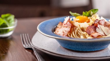 Kızarmış domuz pastırması ile İtalyan makarna spagetti carbonara parmesan peynir ve yumurta sarısı. Restoran tabloda bu. Kopya alanı, seçici odak