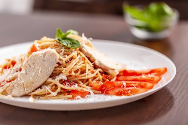 İtalyan makarna spagetti kırmızı domates sosu, domates ve ızgara tavuk. Restoran tabloda bu. Kopya alanı, seçici odak