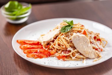 İtalyan makarna spagetti kırmızı domates sosu, domates ve ızgara tavuk. Restoran tabloda bu. Kopya alanı, seçici odak