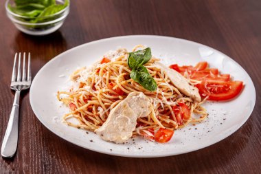 İtalyan makarna spagetti kırmızı domates sosu, domates ve ızgara tavuk. Restoran tabloda bu. Kopya alanı, seçici odak