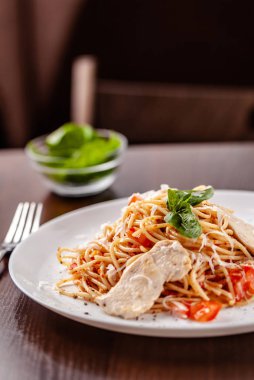 İtalyan makarna spagetti kırmızı domates sosu, domates ve ızgara tavuk. Restoran tabloda bu. Kopya alanı, seçici odak