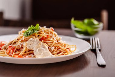 İtalyan makarna spagetti kırmızı domates sosu, domates ve ızgara tavuk. Restoran tabloda bu. Kopya alanı, seçici odak