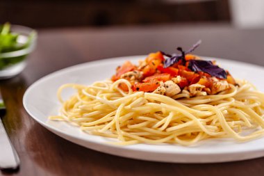 İtalyan makarna spagetti kırmızı domates sosu, domates ve ızgara tavuk. Restoran tabloda bu. Kopya alanı, seçici odak