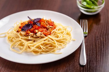 İtalyan makarna spagetti kırmızı domates sosu, domates ve ızgara tavuk. Restoran tabloda bu. Kopya alanı, seçici odak