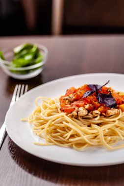 İtalyan makarna spagetti kırmızı domates sosu, domates ve ızgara tavuk. Restoran tabloda bu. Kopya alanı, seçici odak