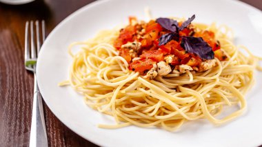 İtalyan makarna spagetti kırmızı domates sosu, domates ve ızgara tavuk. Restoran tabloda bu. Kopya alanı, seçici odak