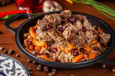 Özbek geleneksel yemekleri. Pilav veya plov kuzu ve bir demir dökme demir kızartma içinde kırmızı Granat ile pan kazan. Arka plan görüntüsü. Kopya alanı, seçici odak