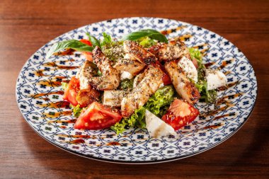 Özbek geleneksel yemekleri. Salata Zarafshon kavrulmuş tavuk fileto, mozzarella peyniri, domates, marul yaprakları, zeytinyağı, hardal sosu. Arka plan görüntüsü. Kopya alanı, seçici odak