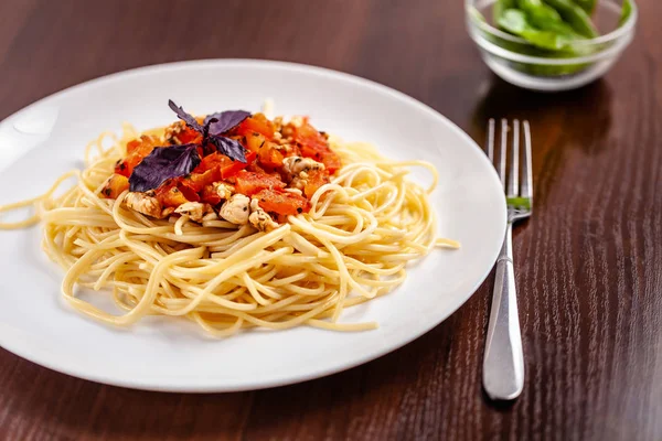 İtalyan makarna spagetti kırmızı domates sosu, domates ve ızgara tavuk. Restoran tabloda bu. Kopya alanı, seçici odak