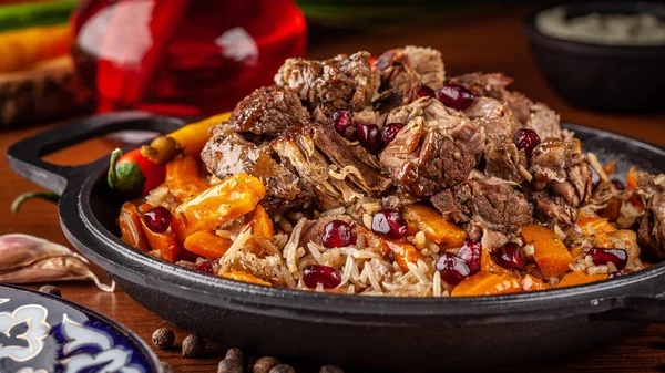 Özbek geleneksel yemekleri. Pilav veya plov kuzu ve bir demir dökme demir kızartma içinde kırmızı Granat ile pan kazan. Arka plan görüntüsü. Kopya alanı, seçici odak