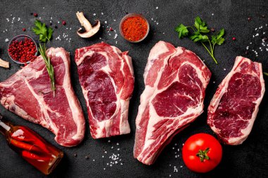 Et çiğ biftek bir siyah arka plan üzerine yalan sebze, domates, marasmade, mantar. arka plan görüntüsü. yan görünüm, kopya alanı, üstten görünüm