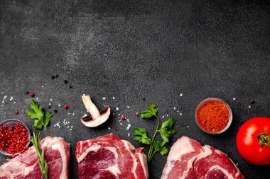 Et çiğ biftek bir siyah arka plan üzerine yalan sebze, domates, marasmade, mantar. arka plan görüntüsü. yan görünüm, kopya alanı, üstten görünüm