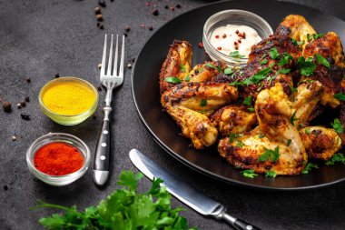 Baharat köri ve siyah bir arka plan üzerinde siyah bir tabakta maydanoz ile Meksika pişmiş tavuk kanatları. yan görünüm, kopya alanı, üstten görünüm